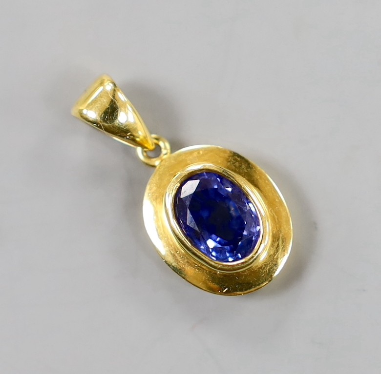 A modern 18k and oval cut sapphire set pendant, overall 22mm, gross weight 3.1 grams.